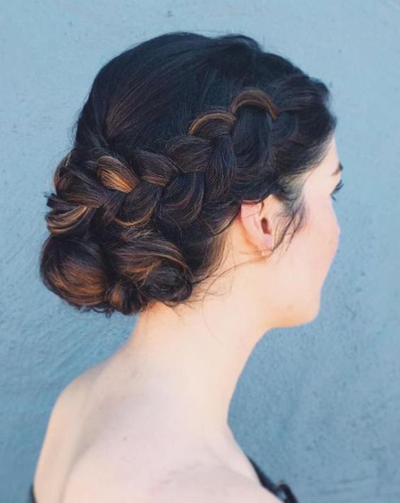 a fully braided low bun with a bump and a touch of mess for a chic boho-inspired bridal look