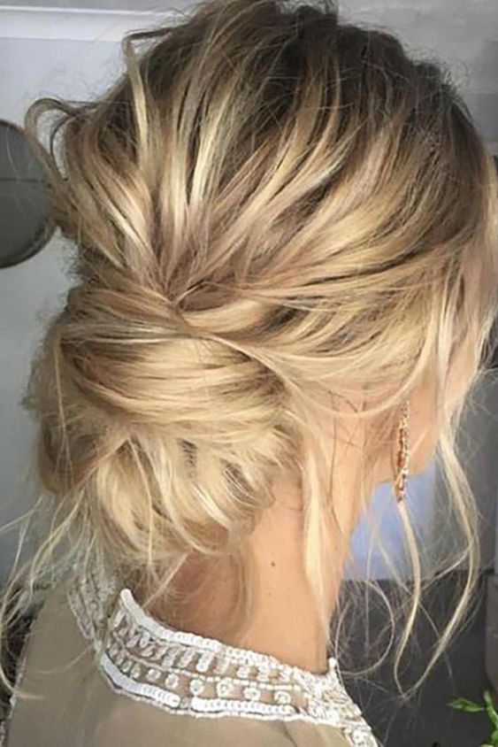 an elegant yet messy low bun with a side braid and some locks down for a cool look