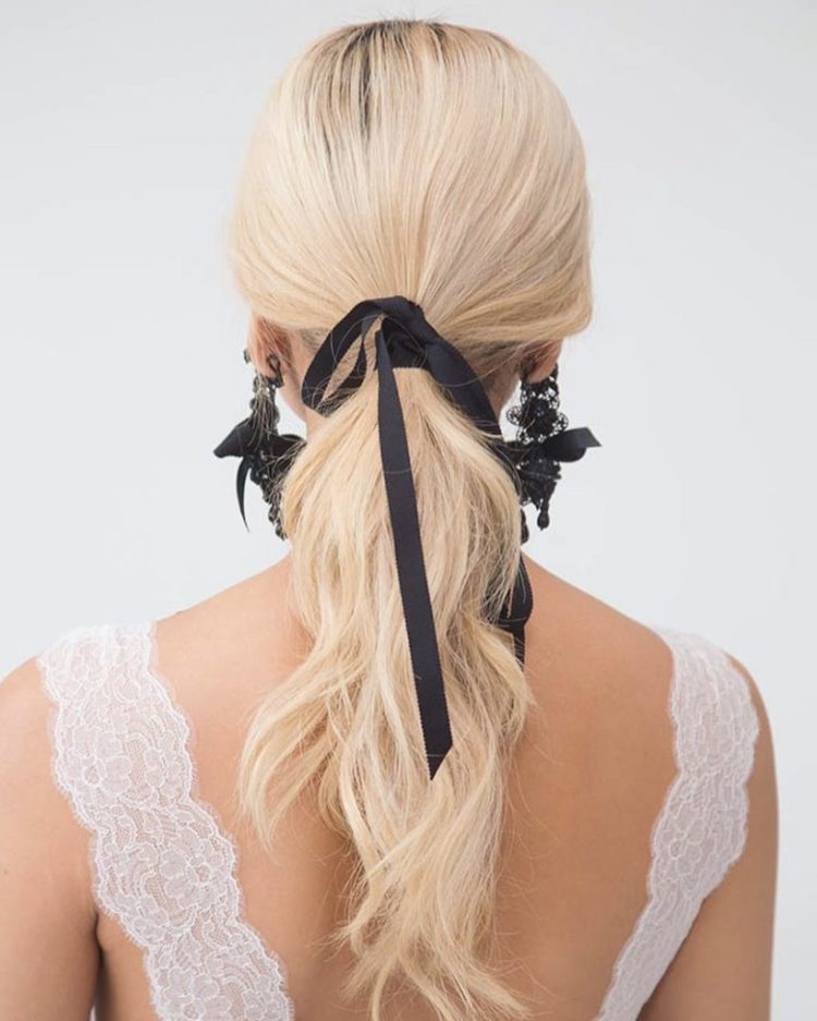 a twisted low ponytail with a sleek top and a black ribbon bow that adds drama to this cute hairstyle