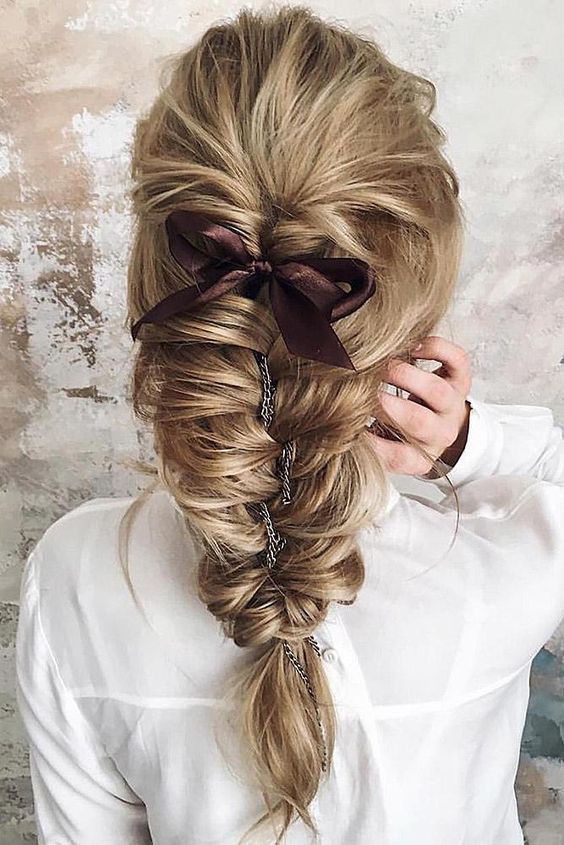a wavy ponytail with a long black velvet ribbon that makes it chic and bold adding a twist to a simple hairstyle