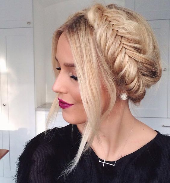 a diagonal braided updo with a low bun and a little hairpiece is great for a modern bride