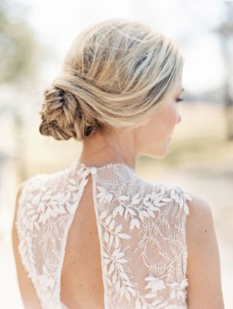 a side braided wavy updo with locks down and some fresh blooms and greenery is great for a boho bride in any season