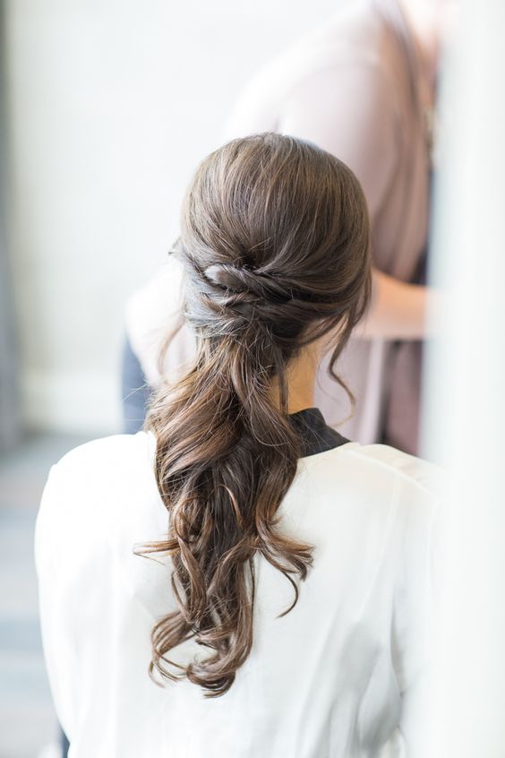 a casual ponytail with waves and twists is perfect for a modern or minimalist bride