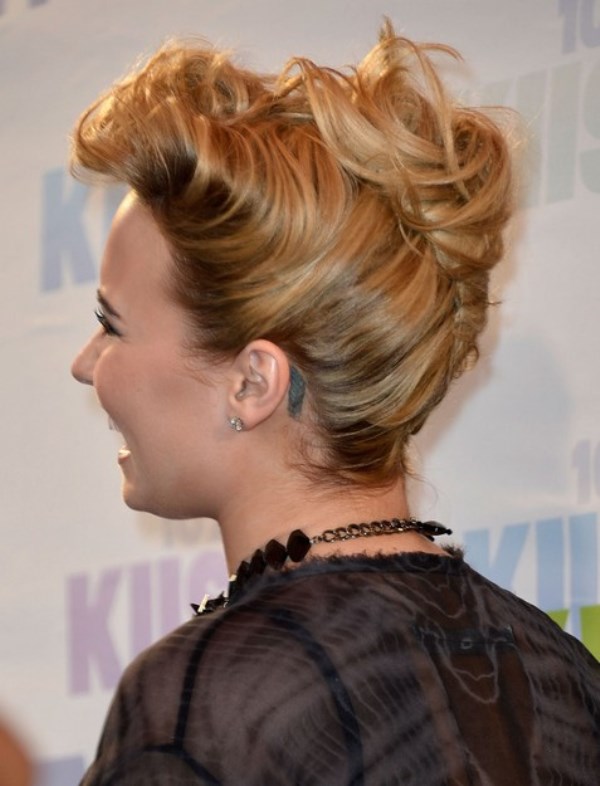 a super messy and chic French twist updo with messy waves and a large rhinestone hairpiece