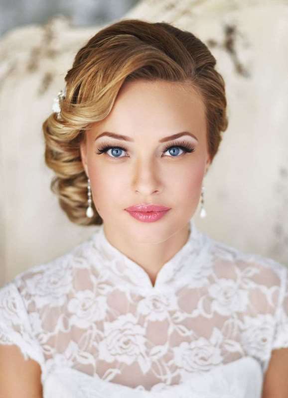 a wavy messy low updo with a volume on top and some locks down is a chic idea for a modern bride