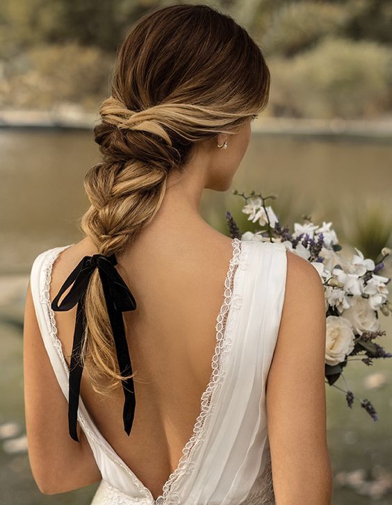 a braided low updo with locks down and an embellished hairpiece looks minimal and edgy