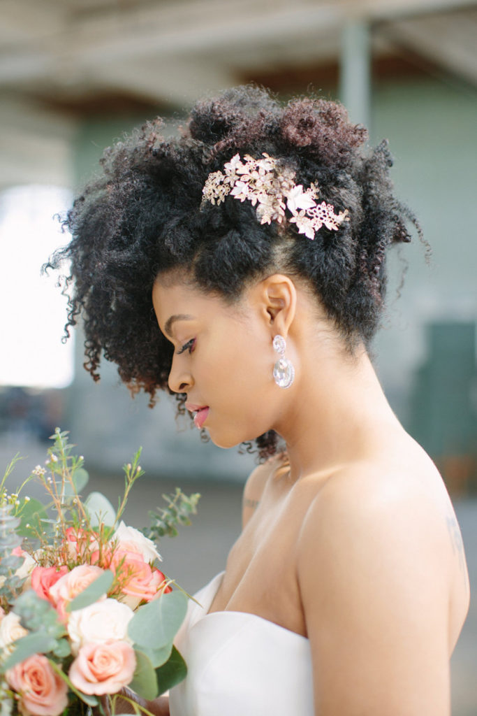 natural curls styled into an updo with many locks down accented with a trendy crystal headpiece
